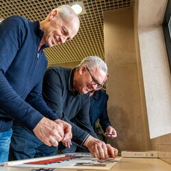 Männer bauen gemeinsam ein Puzzle